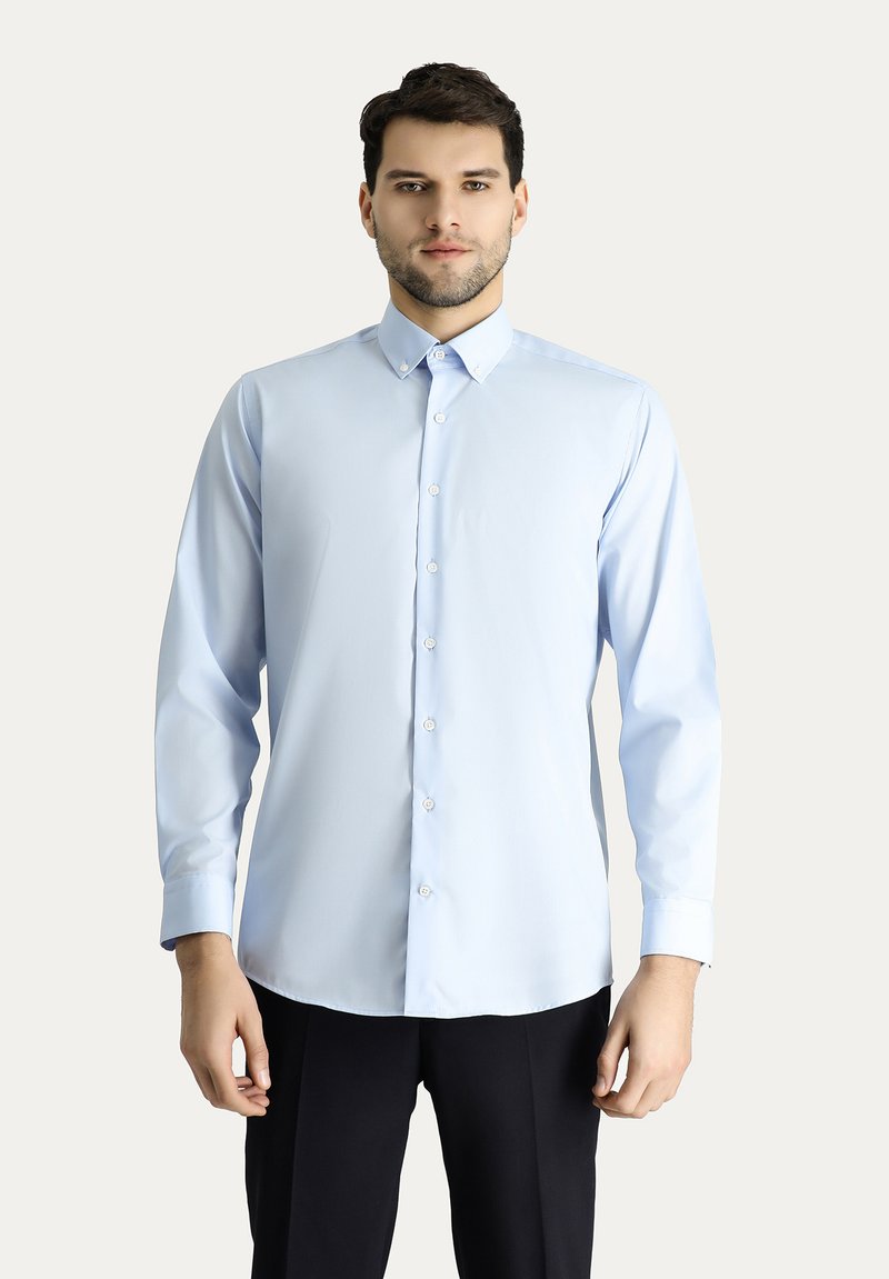 Camicia azzurra chiara con colletto, maniche lunghe e una texture liscia, dotata di bottoni bianchi lungo la parte anteriore.