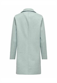 Cappotto lungo in lana verde chiaro, con taglio dritto, collo a rever e cuciture minime. Texture liscia con spacchi laterali all'orlo.