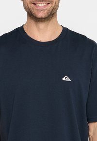 T-shirt in cotone blu navy con scollatura rotonda e maniche corte, dotato di un piccolo logo bianco sulla parte sinistra del petto.