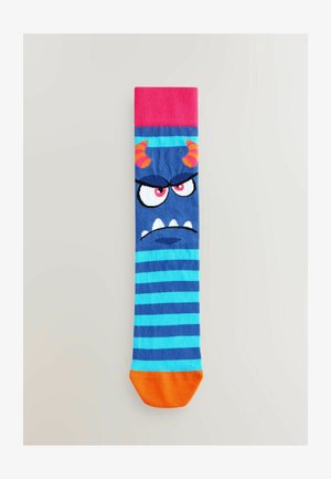 Kék és türkiz csíkos zokni, szörnyeteg mintával, amelynek szarvai, mérges szemei és narancssárga orra van. Bordázott, rózsaszín szegélya.