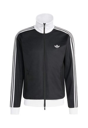 Melna sporta jaka ar augstu apkakli, baltu rāvējslēdzeni un baltām akcentu joslām uz piedurknēm. Uz krūtīm ir neliels balts logotips un sānu kabatas.