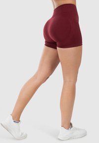 Bordeaux hoge taille shorts in een strakke pasvorm, met een gladde textuur. Gepaard met witte sportieve schoenen met een bovenwerk van mesh.