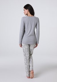 Maglietta grigia a maniche lunghe abbinata a pantaloni grigio chiaro con motivo a foglie di palma. Tessuto morbido con un design aderente e collo rotondo semplice.