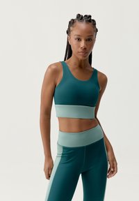 Top corto deportivo y leggings de cintura alta en verde azulado y verde menta. Textura suave con un diseño ajustado y acentos de color contrastantes.