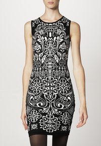 Vestito nero senza maniche con intricate fantasie floreali e geometriche bianche, design aderente, tessuto morbido, stile al ginocchio.