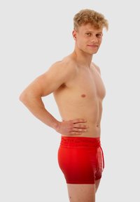 Rode zwembroek met een trekkoord, een gladde textuur en een aansluitend ontwerp. De tailleband heeft het "BeActive" logo.