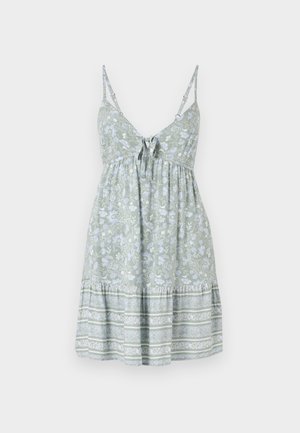 Ανοιχτό πράσινο λουλουδάτο φόρεμα με ρυθμιζόμενους λεπτούς ιμάντες, φιόγκο μπροστά και στρoγγυλή φούστα με tiers και αντίθετα λευκά και μπλε σχέδια.