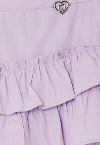 Tessuto viola con strati arricciati e un piccolo accento a forma di cuore in argento. Testura liscia, design leggero e un sottile luccichio.