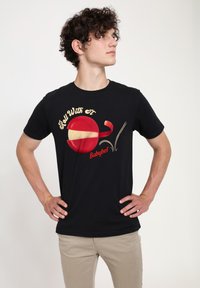 Sort bomuld t-shirt med et rødt og gult Babybel ost grafik med teksten "Roll With It." Korte ærmer og rund halsudskæring.