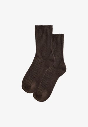 Paar dunkelbraune gerippte Strick-Crew-Socken flach ausgelegt, die Textur und Form zeigend, auf weißem Hintergrund.