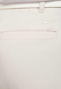 Svetle bež Nike hlače z gladko teksturo, ozkim krojem in zadnjim žepom z diskretno vezeno blagovno znamko.