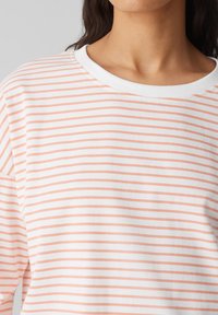 Leichtes Langarmoberteil in Weiß mit pfirsichfarbenen horizontalen Streifen, ausgestattet mit einem weiten Rundhalsausschnitt und weichem Material.