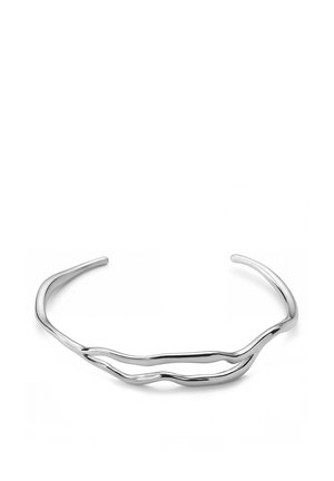 Avoin hopeinen rannerenkas, jossa kaksi aaltoilevaa, lomittain kietoutunutta nauhaa muodostavat abstraktin, minimalistisen muotoilun.