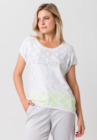 Witte top met korte mouwen, met een circulair patroon, een verloop in groene accenten aan de onderrand en een strass-tekstontwerp aan de voorkant.