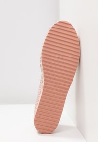 Semelle de chaussure à texture côtelée, de couleur rose, avec une forme légèrement arrondie. Le matériau semble être du caoutchouc avec un design antidérapant texturé.