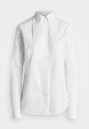 Chemise blanche à manches longues avec col pointu et détails plissés verticaux sur le devant.