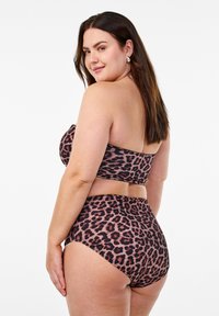 Bikini set s uzorkom leopard, koji se sastoji od bez naramenica gornjeg dijela i gaćica visokog struka. Izrađen od glatkog materijala mekanog teksture u nijansama smeđe i pješčane boje.
