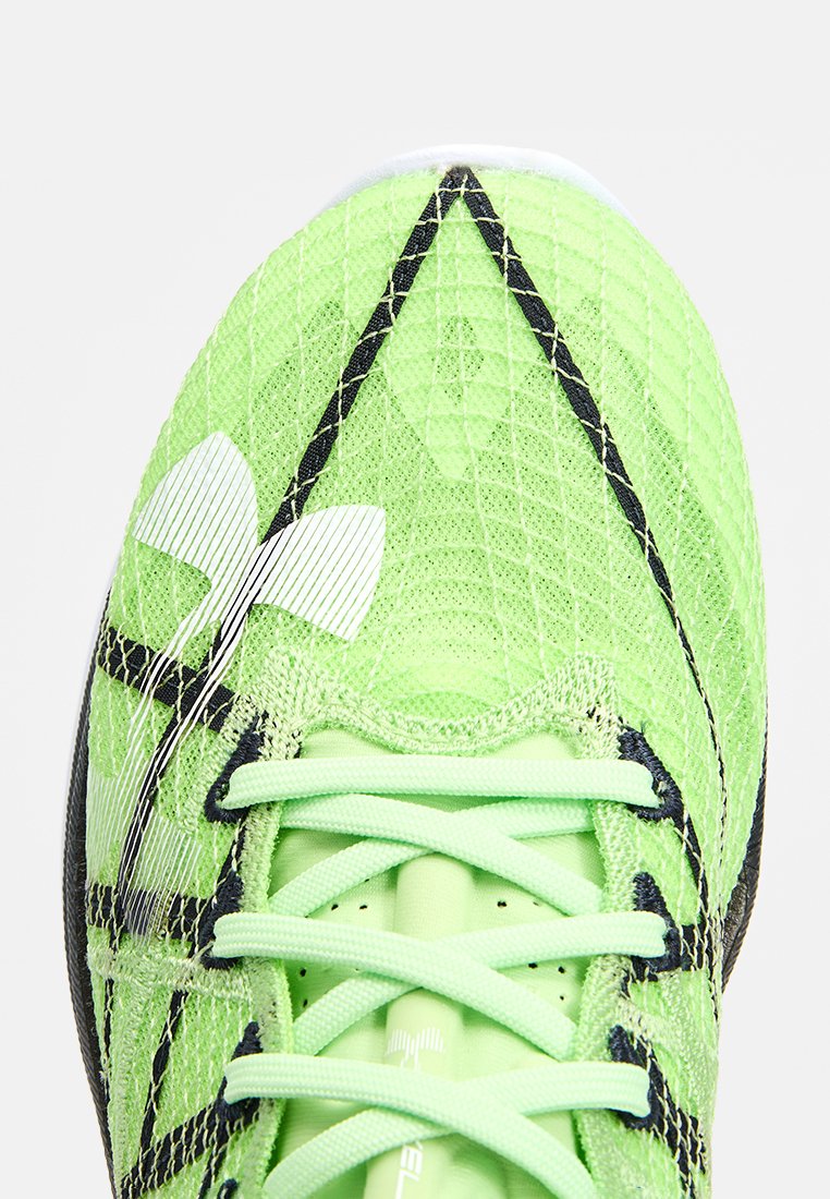 Scarpa sportiva verde con tomaia in mesh testurizzato, dettagli neri e logo bianco. Include lacci piatti e dettagli con un motivo intricato.