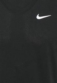 Camiseta deportiva negra hecha de tejido transpirable, con un sutil patrón texturizado y un logotipo blanco de Nike en el pecho.