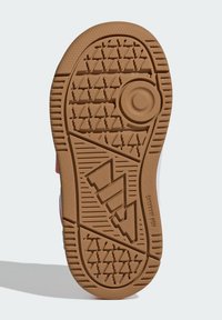 Podošva topánky z gumovej gumy so vzorom behúňa v tvare cik-caku a trojuholníkov. Dizajn obsahuje kruhový emblém v strede pre lepšiu trakciu.