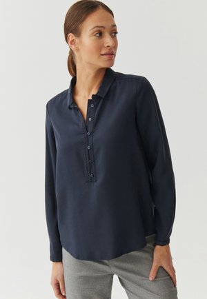Navyblauw overhemd met lange mouwen en kraag, met een gebuttonneerde sluiting en een gladde textuur. Geknipt in een relaxte pasvorm met zijsplitten.