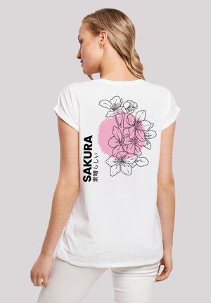 Weißes T-Shirt mit kurzen Ärmeln, das ein pinkfarbenes Kreisdesign mit einer schwarzen Sakura-Blumenillustration und japanischem Text auf dem Rücken zeigt.