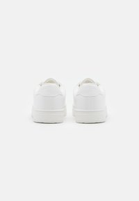 Zapatillas blancas con parte superior de cuero suave, puntera redondeada, cuello acolchado y suela de goma. Diseño minimalista sin marcas visibles.