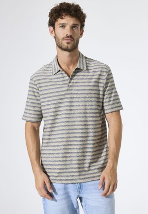 Polo de manga corta en beige con rayas horizontales azul marino, con cuello con solapas y un ajuste relajado. Textura suave y diseño informal.
