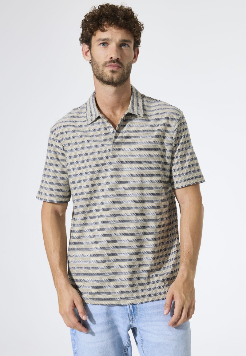 Polo a maniche corte beige con righe orizzontali blu navy, dotata di scollo con colletto e vestibilità comoda. Tessuto morbido e design casual.