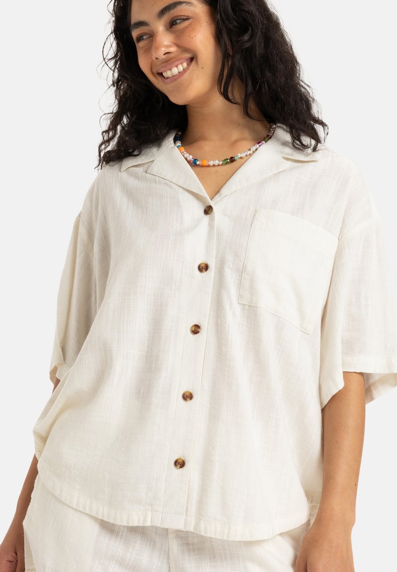 Cream-colored, short-sleeve shirt in lightweight fabric with a pocket, five wooden buttons, and a relaxed fit.
