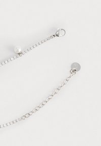 Bracciale in argento con cristalli trasparenti e un singolo accento di perla, dotato di chiusura a moschettone e etichetta loggata circolare. Maglie testurizzate.