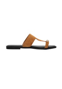 Tan suède slip-on sandaal met een vlakke zwarte zool, met een V-vormige band en een metallic accentparel bij de teen.