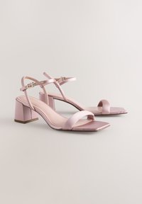 Sandali con tacco a blocco in satin rosa tenue con punta quadrata, dotati di sottili cinturini alla caviglia e plantari lisci e strutturati.