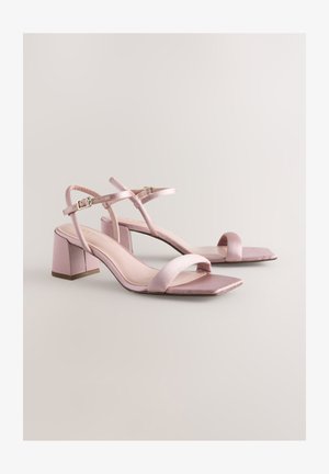 Basām kurpēm ar bloku papēdi mīkstā rozā satīnā, kvadrātveida pirkstu daļa, ar plānām potīšu siksnām un gludiem, fakturētiem zolīšu virsmām.