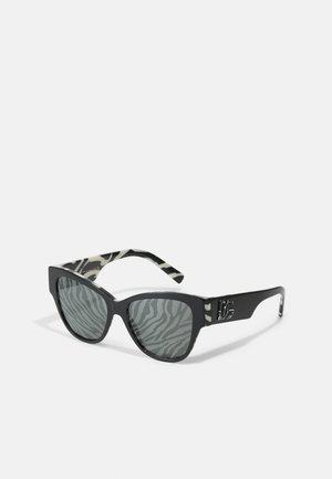 Ochelari de soare negri cu formă de ochi de pisică, cu lentile gri cu model zebra și un design pe temple cu dungi negre și albe, având un accent cu logo.