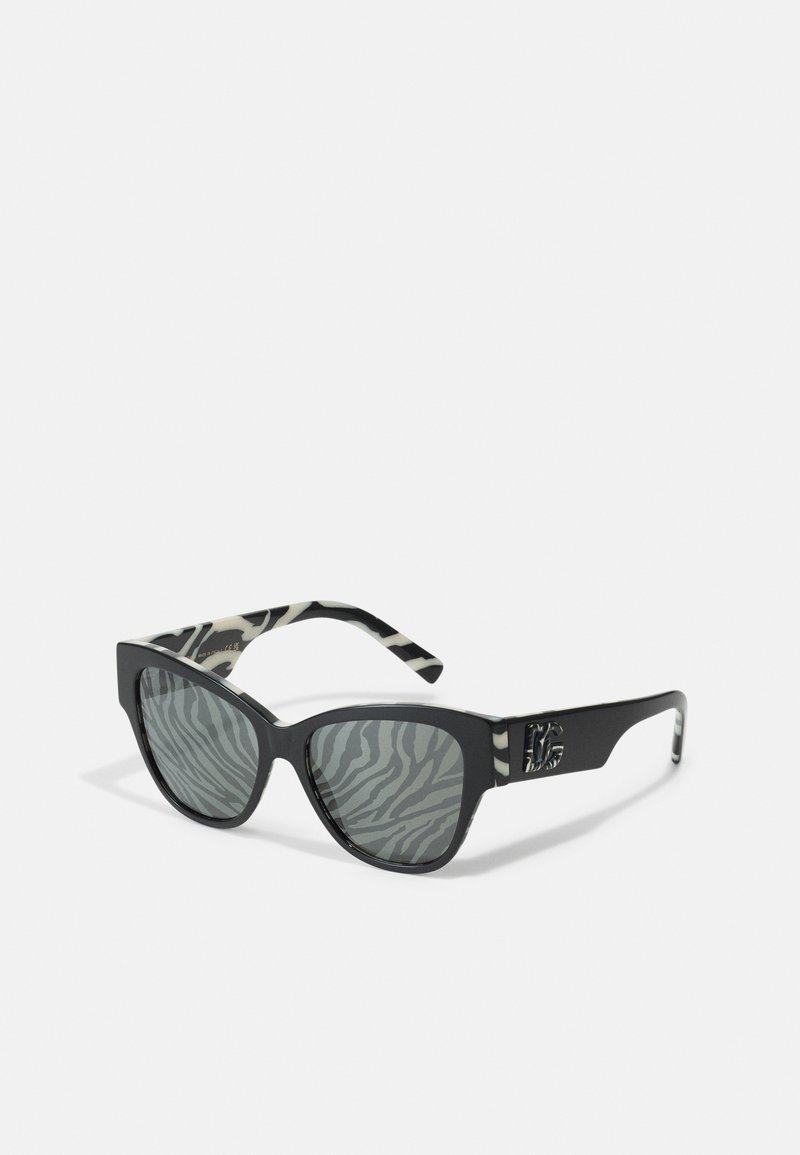 Ochelari de soare negri cu formă de ochi de pisică, cu lentile gri cu model zebra și un design pe temple cu dungi negre și albe, având un accent cu logo.