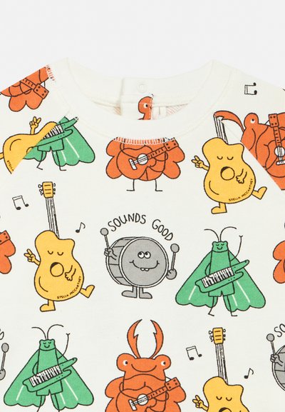 Tegnefilm-musikinstrumenter og dyr på stof: gule guitarer, orange krabber med guitarer, grå trommer med "Sounds Good" og grønne insekter med klaver.