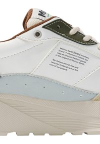 Hvite sneakers med teksturert gummisåle, grønne og brune detaljer, og en glatt overflate med en etikett om miljøvennlige materialer.