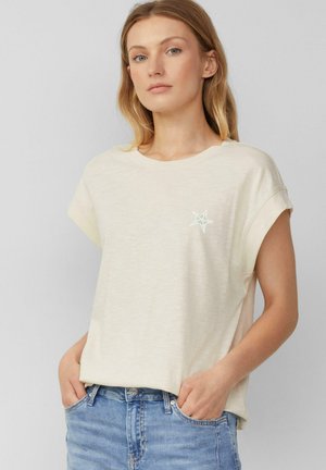 Crème kleurige t-shirt met korte mouwen, gemaakt van zachte stof, met een kleine multikleurige sterafbeelding op de linkerborst en een losse pasvorm.