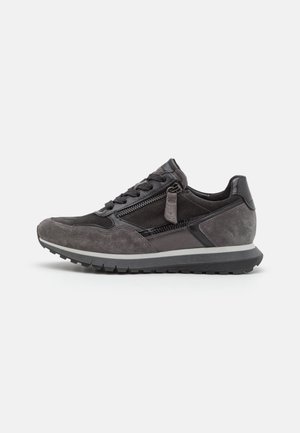 Baskets en daim gris avec un accent en cuir noir, présentant un design à lacets et une fermeture éclair sur le côté. Semelle en caoutchouc avec un motif texturé.