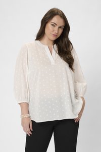 Blouse blanche avec un col, ornée de pois texturés. Manches bouffantes 3/4 et coupe ample. Assortie avec un pantalon noir.