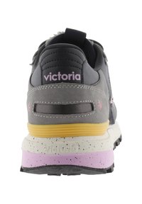 Grijze en zwarte sneaker met een textuur bovenwerk, roze en gele accenten, een gevoerde zool en een aantrek lus aan de hiel, met het merknaam erop.