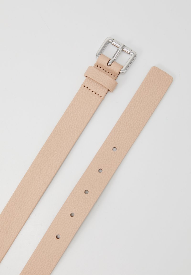 Ceinture en cuir beige texturé avec boucle en métal argenté et plusieurs trous d'ajustement sur un fond clair uni.