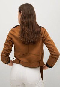 Giacca in suede marrone con un design aderente, dotata di una cintura in vita, maniche lunghe e dettagli neri ai polsini.