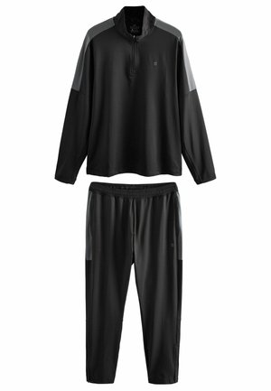 Schwarzer Sportanzug, bestehend aus einem langärmligen Oberteil mit Viertel-Reißverschluss und grauen Akzenten sowie passenden schmal geschnittenen Hosen mit elastischem Bund.