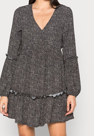 Robe noire à petits motifs floraux blancs, col en V, manches longues bouffantes, ourlet à volants et texture de tissu douce.