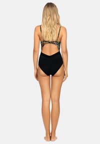 Jednoczęściowy strój kąpielowy z kolorowym, wzorzystym góra i czarnym dołem. Posiada otwarty tył i regulowane ramiączka. Gładka faktura.