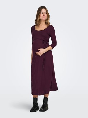 Zwangerschapsjurk in donkerpaars, gemaakt van zachte stof. Heeft een ronde hals, driekwart mouwen en een strikdetail in de taille.