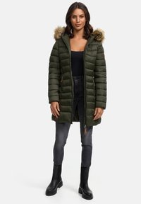 Olive green puffer coat with a detachable faux fur hood, zippered front, and side pockets. Paired with black slim jeans and knee-high boots.