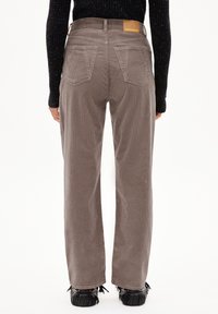 Brown corduroy wide-leg pants with textured fabric, patch back pockets, and a branded leather label on the waistband.